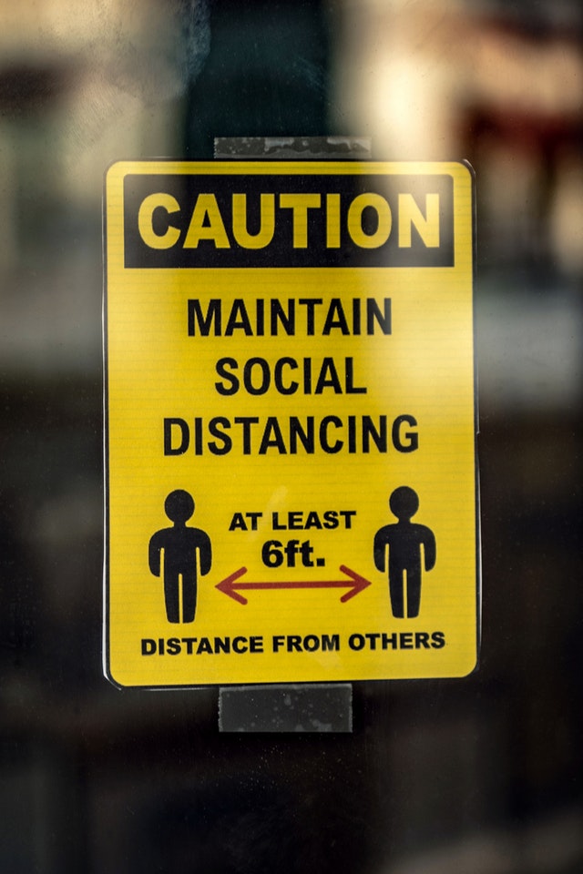 yellow and black caution social distance sign